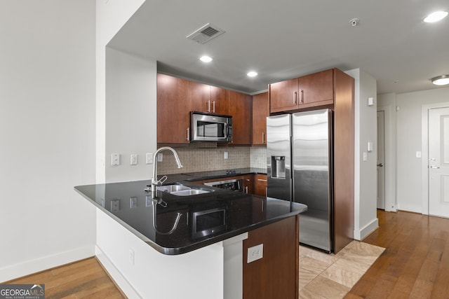 kitchen with appliances with stainless steel finishes, kitchen peninsula, sink, and backsplash