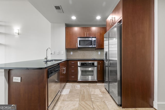 kitchen featuring tasteful backsplash, appliances with stainless steel finishes, kitchen peninsula, and sink