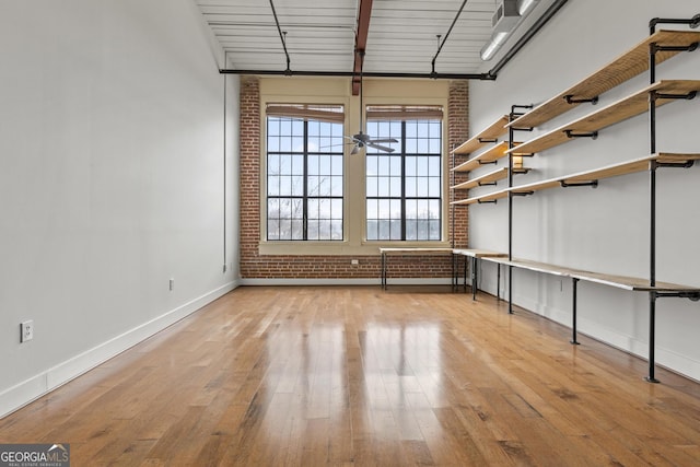 unfurnished room with light wood-type flooring and brick wall