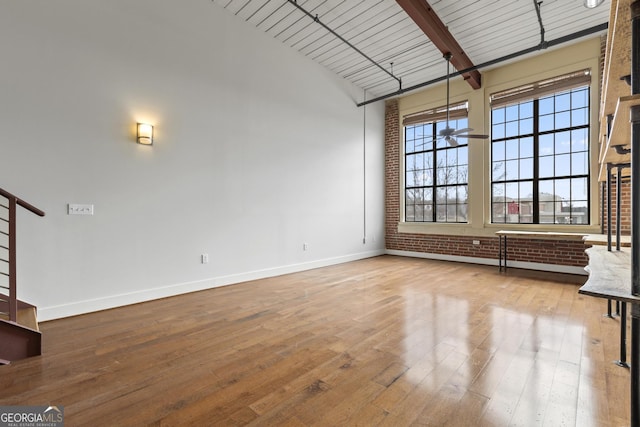 interior space with vaulted ceiling with beams, light hardwood / wood-style flooring, wooden ceiling, and brick wall