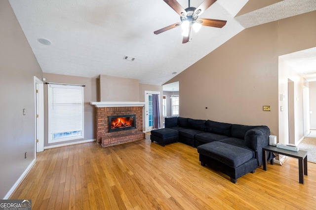 living room featuring ceiling fan, a brick fireplace, high vaulted ceiling, and light hardwood / wood-style floors