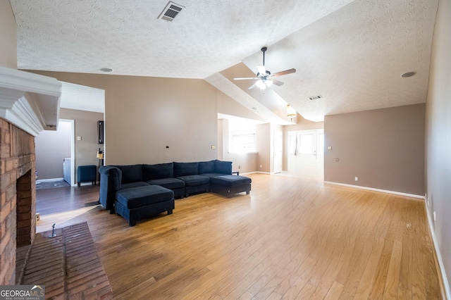 living room featuring lofted ceiling, a fireplace, hardwood / wood-style floors, and a textured ceiling