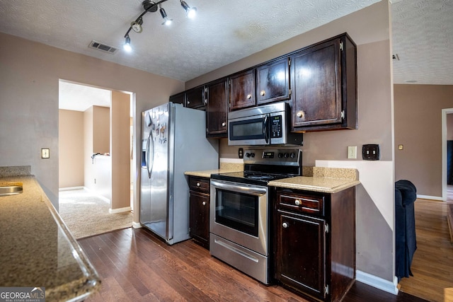 kitchen with dark wood-type flooring, rail lighting, dark brown cabinets, a textured ceiling, and appliances with stainless steel finishes