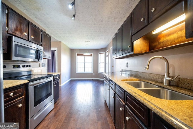 kitchen featuring appliances with stainless steel finishes, pendant lighting, sink, dark wood-type flooring, and a textured ceiling