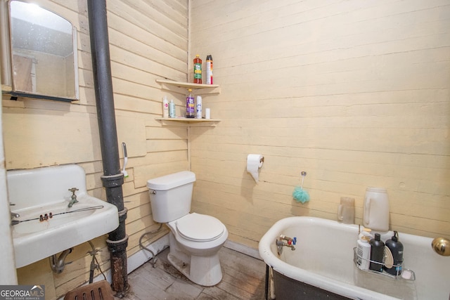 bathroom featuring hardwood / wood-style floors, a washtub, and toilet