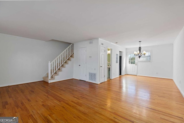 unfurnished living room featuring an inviting chandelier and light wood-type flooring