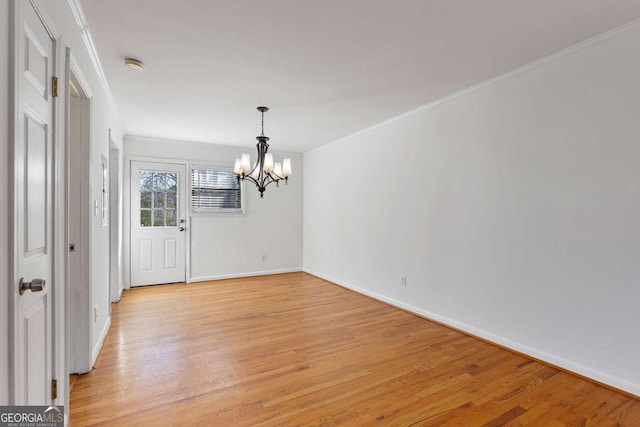 unfurnished room featuring ornamental molding, light hardwood / wood-style floors, and a notable chandelier