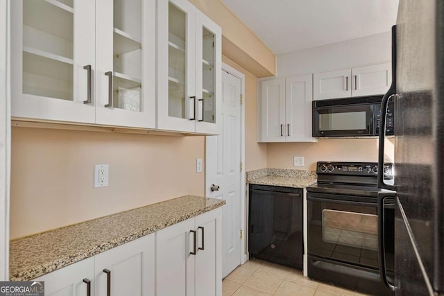 kitchen featuring white cabinetry, light stone countertops, light tile patterned flooring, and black appliances