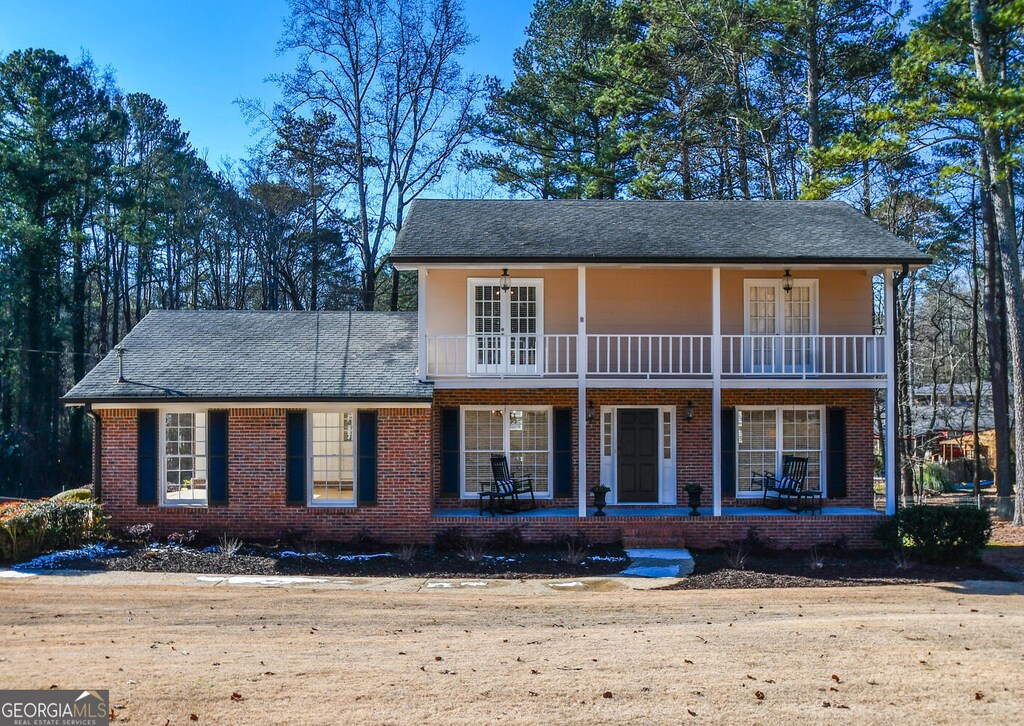1357 Ridgewood Dr, Lilburn, GA 30047 - view of front of house featuring a porch, brick siding, ceiling fan, and a balcony