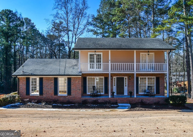 view of front of house featuring a porch, brick siding, ceiling fan, and a balcony