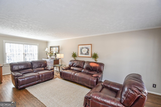 living room with ornamental molding, a textured ceiling, baseboards, and wood finished floors