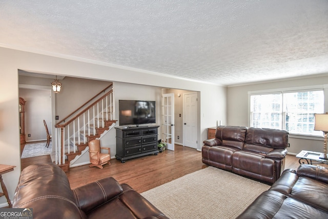 living area featuring baseboards, a textured ceiling, stairway, and wood finished floors