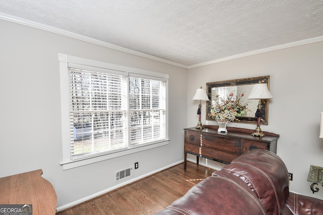 living area featuring baseboards, a textured ceiling, visible vents, and wood finished floors