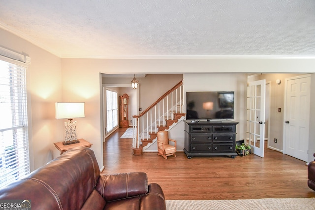 living area featuring a textured ceiling, stairway, wood finished floors, and ornamental molding