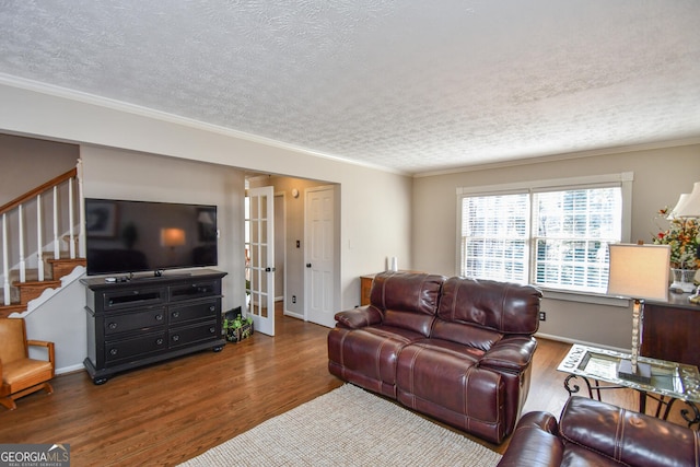 living area featuring a textured ceiling, wood finished floors, french doors, ornamental molding, and stairway