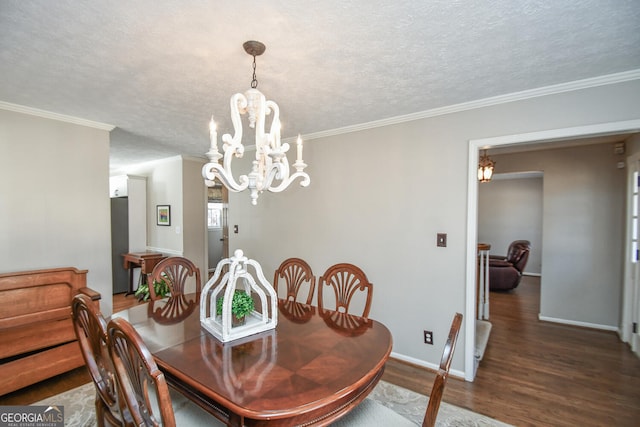 dining space featuring a textured ceiling, ornamental molding, wood finished floors, and baseboards