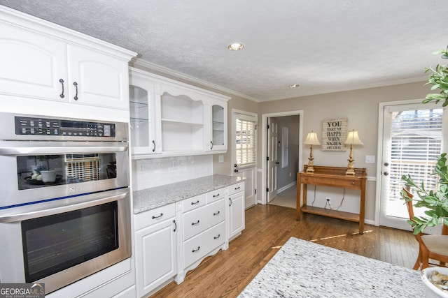 kitchen featuring double oven, white cabinetry, a wealth of natural light, and light wood-style floors