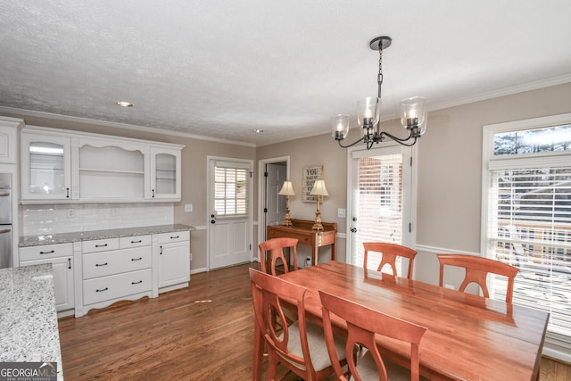 dining room featuring a textured ceiling, ornamental molding, wood finished floors, and an inviting chandelier