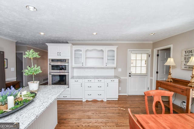 kitchen featuring double oven, white cabinets, light wood-style floors, and glass insert cabinets