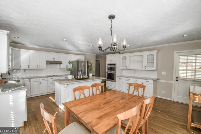 dining area with dark wood-style floors, baseboards, a chandelier, and crown molding