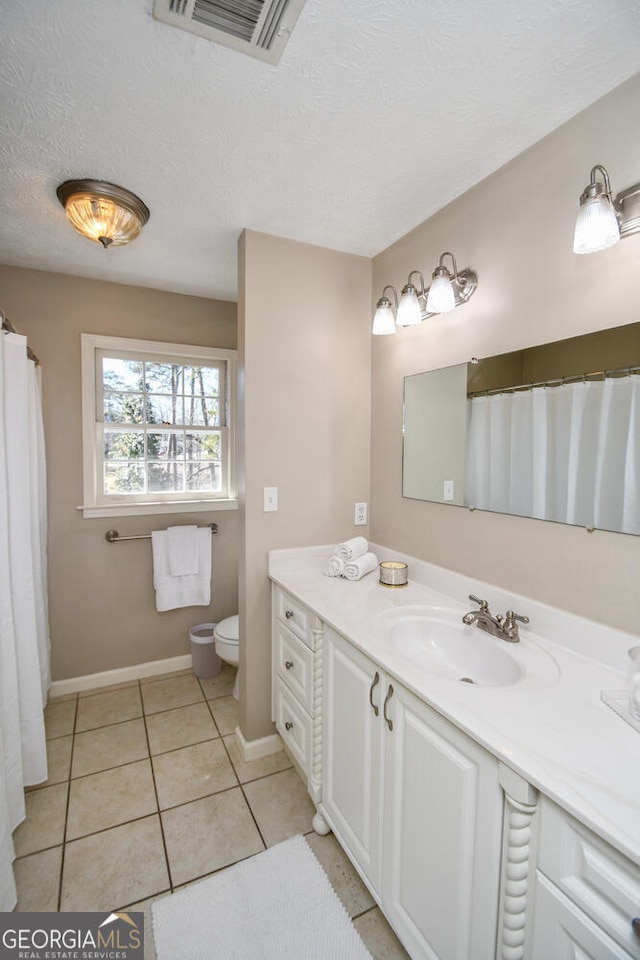 bathroom featuring visible vents, toilet, a textured ceiling, vanity, and tile patterned floors