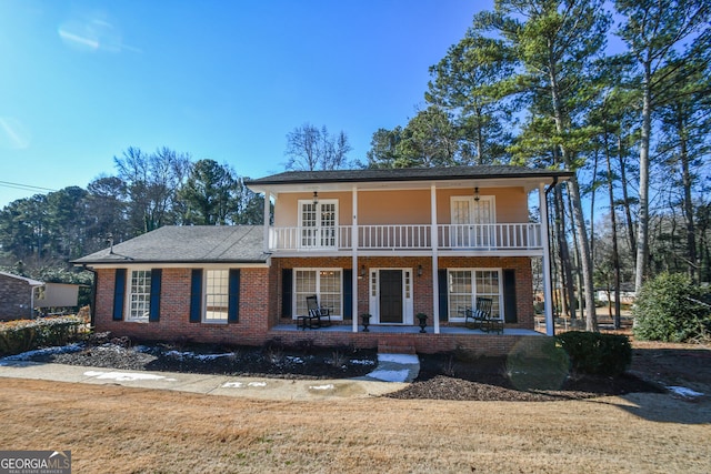 front of property featuring covered porch, brick siding, ceiling fan, and a balcony