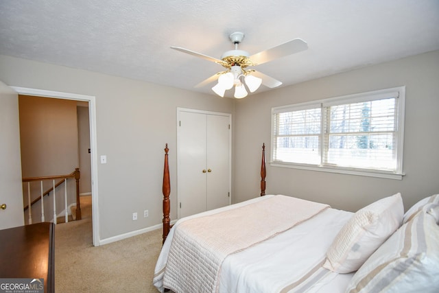 bedroom with light carpet, baseboards, ceiling fan, a textured ceiling, and a closet