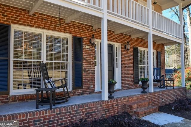 doorway to property featuring covered porch and brick siding