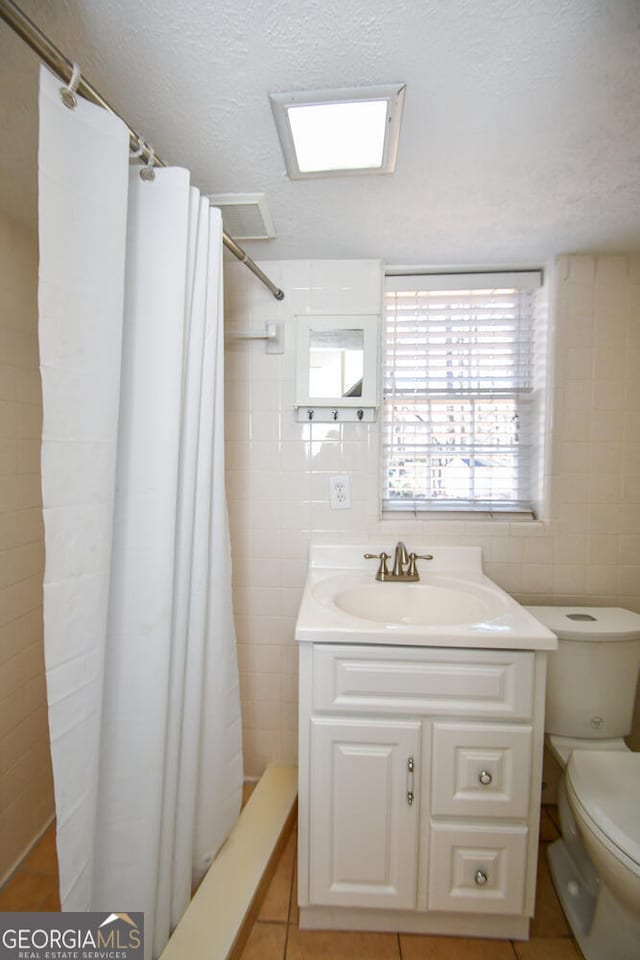 full bath featuring curtained shower, toilet, vanity, and tile walls