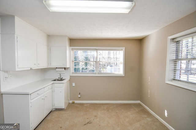 kitchen featuring light carpet, light countertops, a sink, and a healthy amount of sunlight