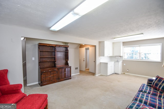 living room with visible vents, baseboards, a textured ceiling, and light colored carpet