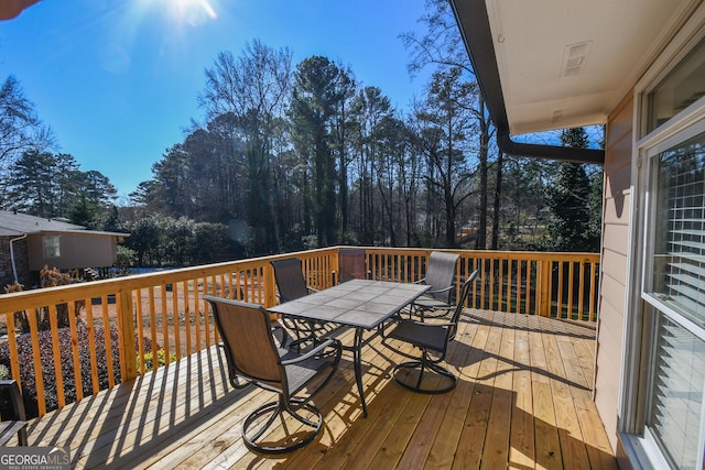 wooden deck with outdoor dining area and visible vents