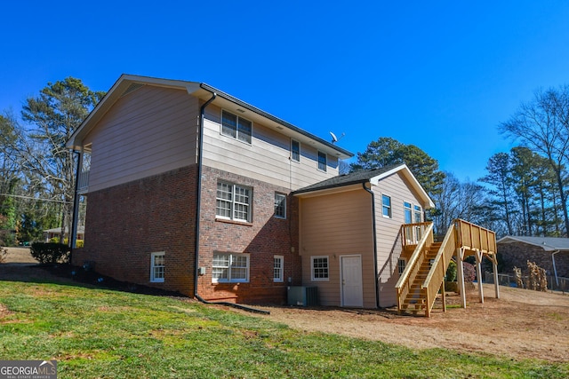 back of property featuring a wooden deck, stairs, a yard, central air condition unit, and brick siding