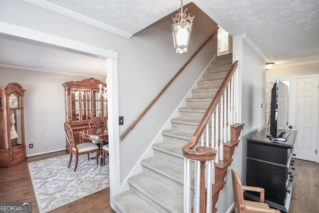 staircase featuring crown molding, a textured ceiling, a chandelier, and wood finished floors