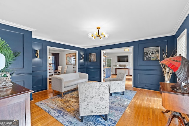 living room featuring crown molding, a notable chandelier, and light wood-type flooring