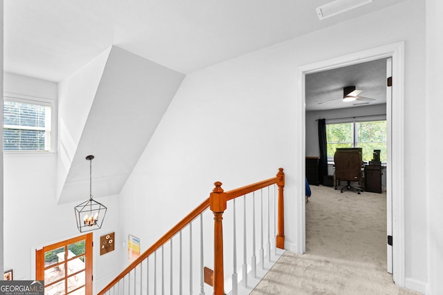 corridor featuring an inviting chandelier and light carpet