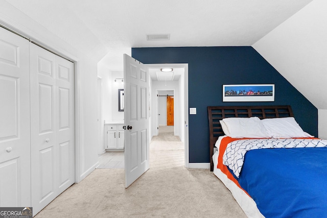 bedroom featuring light colored carpet, vaulted ceiling, and a closet