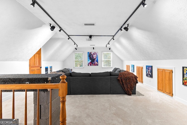 living room featuring lofted ceiling, light colored carpet, rail lighting, and a textured ceiling