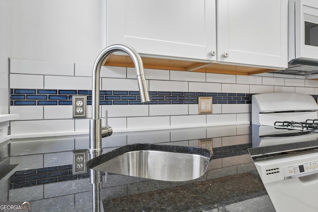 room details with sink, range, white cabinetry, dark stone countertops, and tasteful backsplash