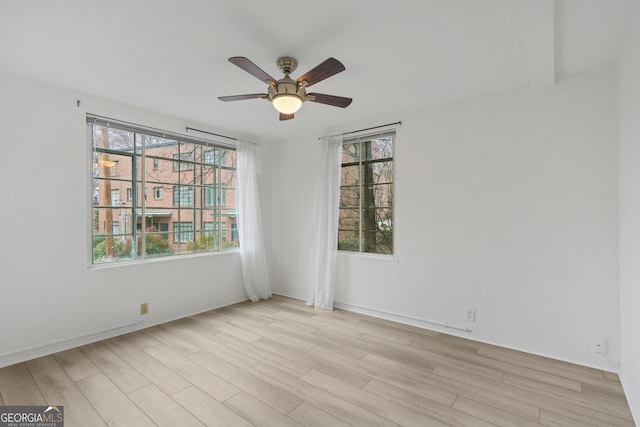 spare room featuring a wealth of natural light, light hardwood / wood-style floors, and ceiling fan