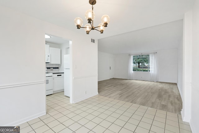 empty room with vaulted ceiling, light tile patterned floors, and a chandelier