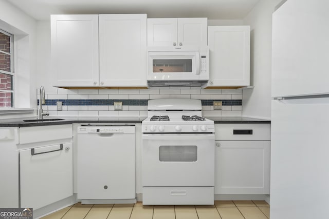 kitchen with light tile patterned flooring, sink, white cabinetry, white appliances, and decorative backsplash