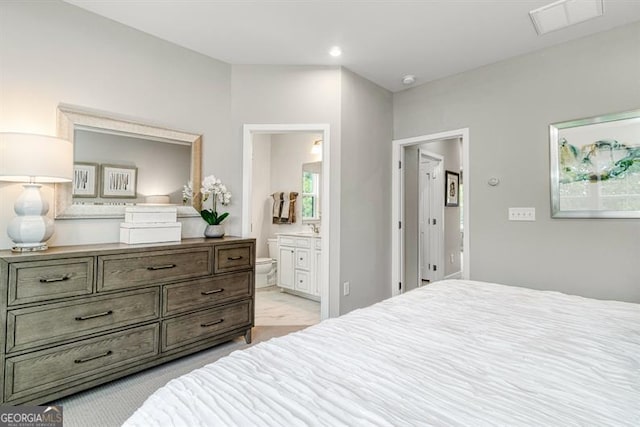 bedroom featuring ensuite bathroom and light carpet