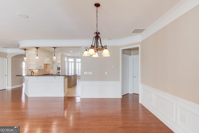 6706 Amherst Dr, Hoschton, GA 30548 - kitchen with dark countertops, a chandelier, crown molding, light wood-type flooring, and pendant lighting