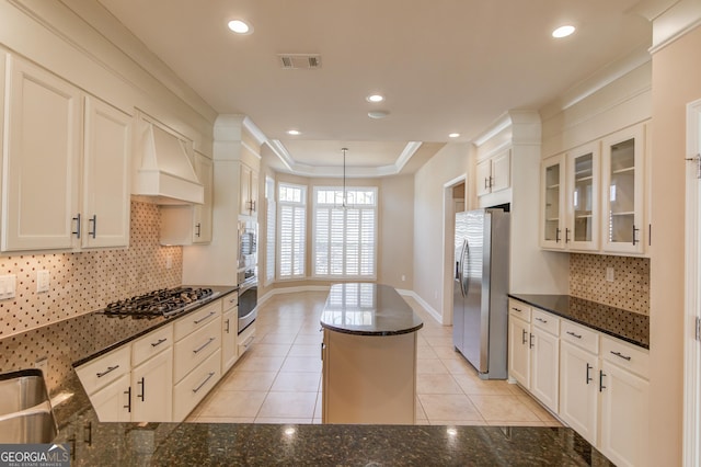 kitchen with premium range hood, appliances with stainless steel finishes, dark stone countertops, and white cabinets