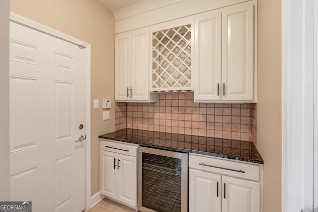 bar with white cabinetry, dark stone countertops, beverage cooler, and decorative backsplash