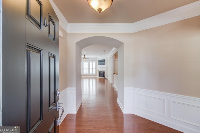 6706 Amherst Dr, Hoschton, GA 30548 - entrance foyer with arched walkways, ornamental molding, a fireplace, a wainscoted wall, and a decorative wall
