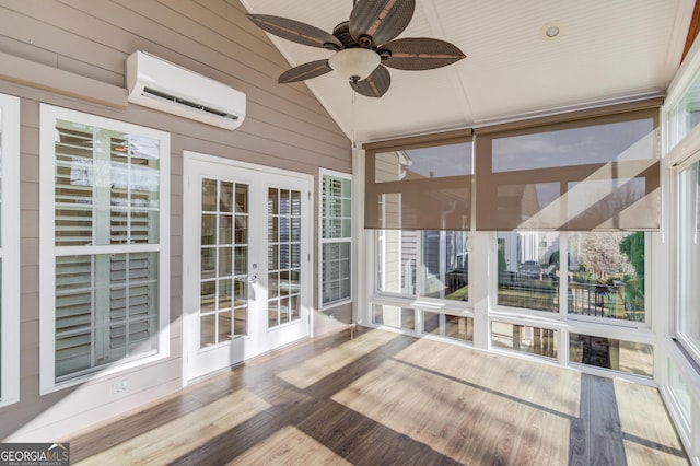 unfurnished sunroom featuring lofted ceiling, plenty of natural light, a wall unit AC, and french doors