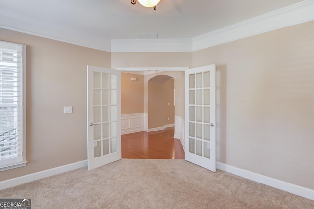 carpeted spare room featuring ornamental molding and french doors