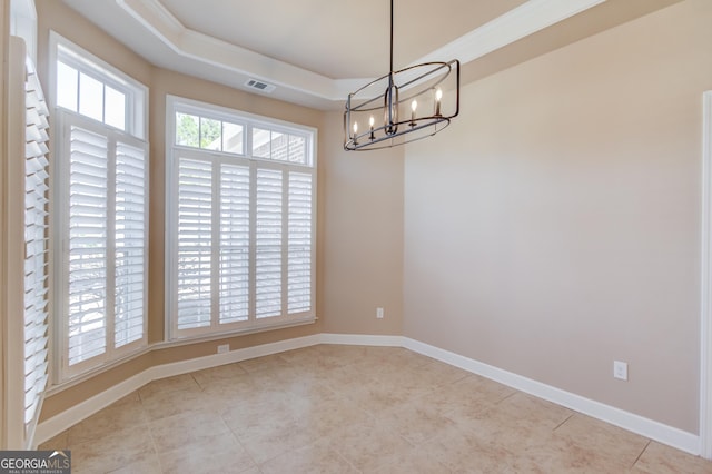 spare room featuring a healthy amount of sunlight, a tray ceiling, a chandelier, and light tile patterned floors